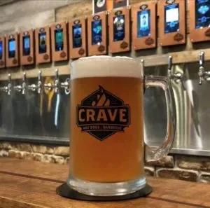 Beer mug with "CRAVE" logo in front of self-serve taps.