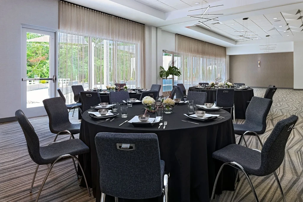 Bright, modern event room with elegantly set black-draped tables.