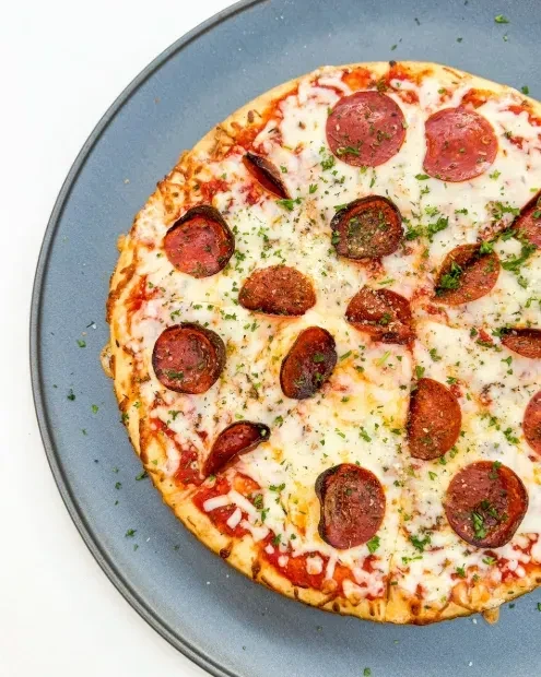 Overhead close-up of a pepperoni pizza with melted cheese and herbs.