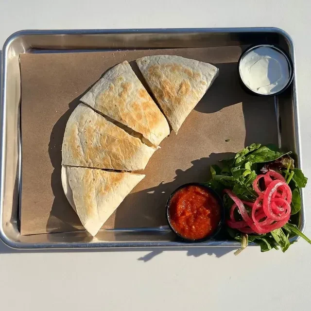 Golden quesadilla triangles, sour cream, red salsa, and side salad on tray.