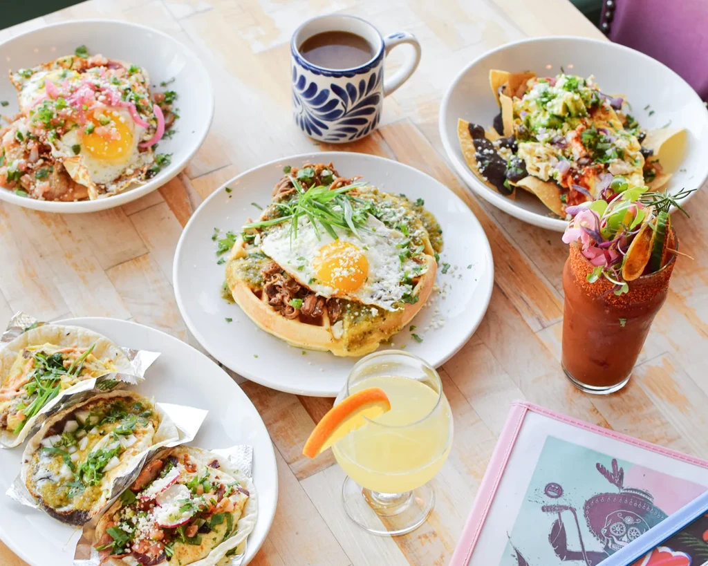 Overhead view of a table filled with various brunch dishes and colorful drinks.