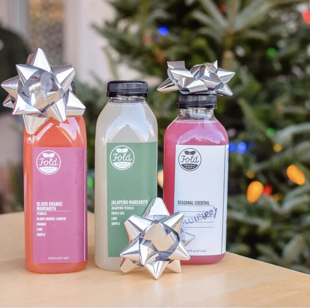 Three Fold Botanas Bar bottled cocktails, festive with bows and tree lights.