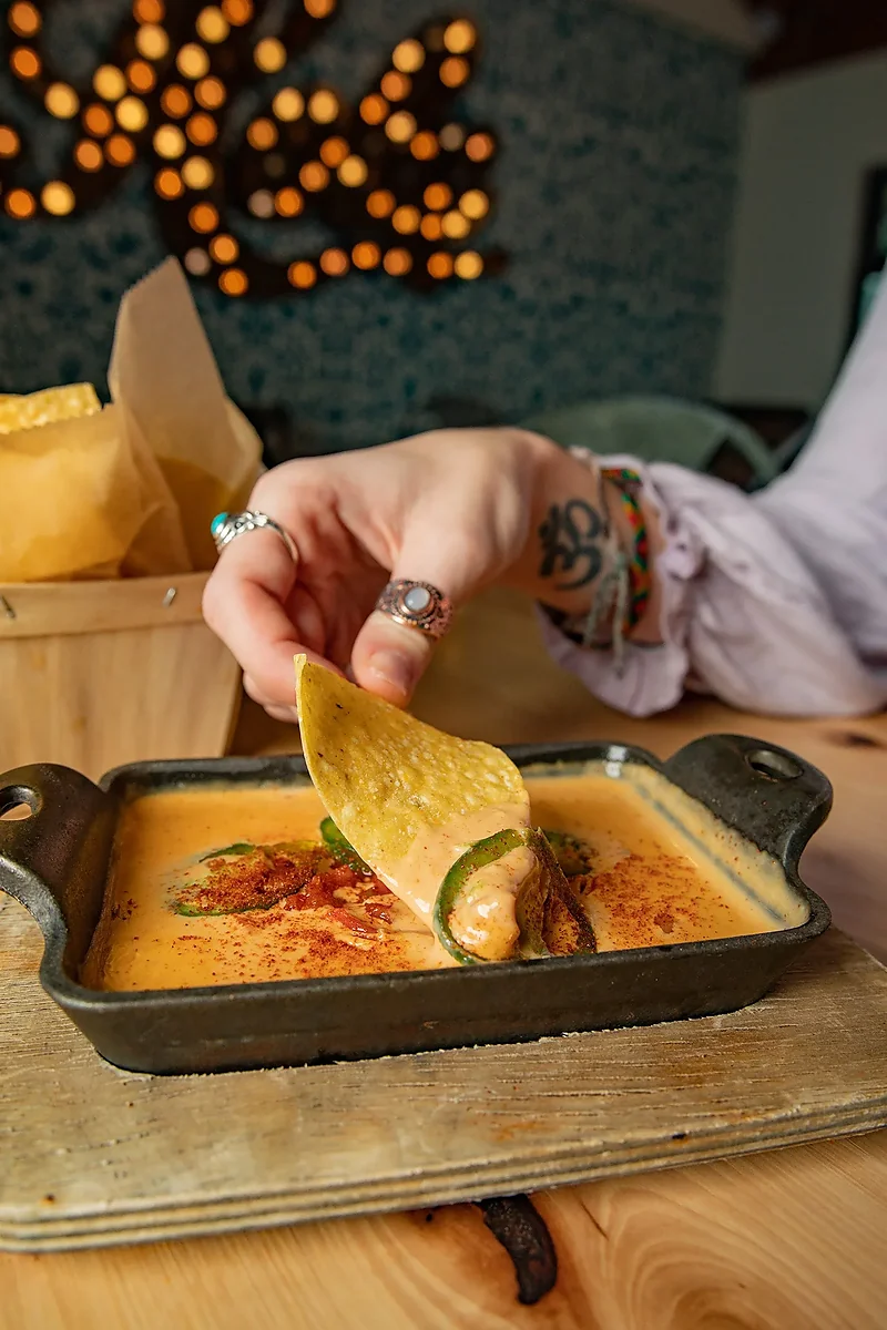 Skillet of cheese dip with a tortilla chip being dipped