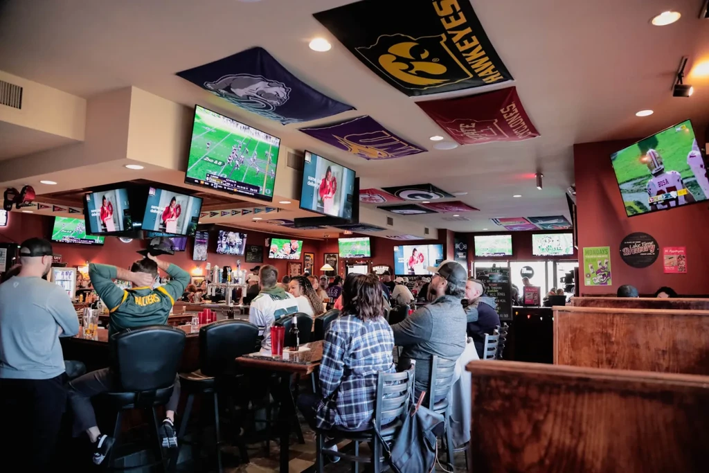 Vibrant sports bar filled with people, TVs, and team memorabilia.