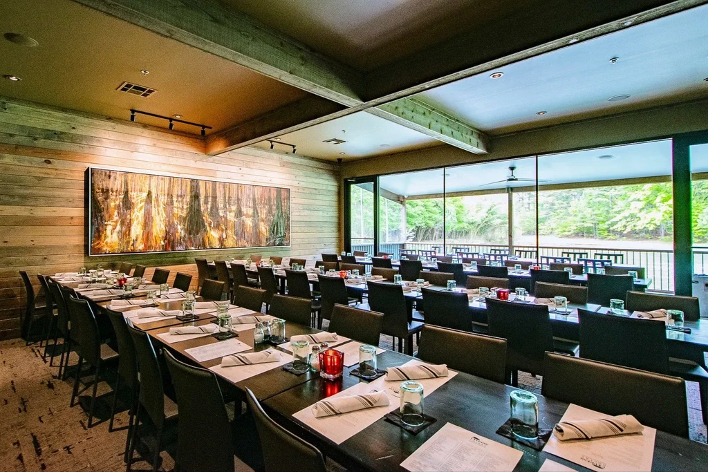 Modern dining room, set tables, wood walls, abstract art, patio view.