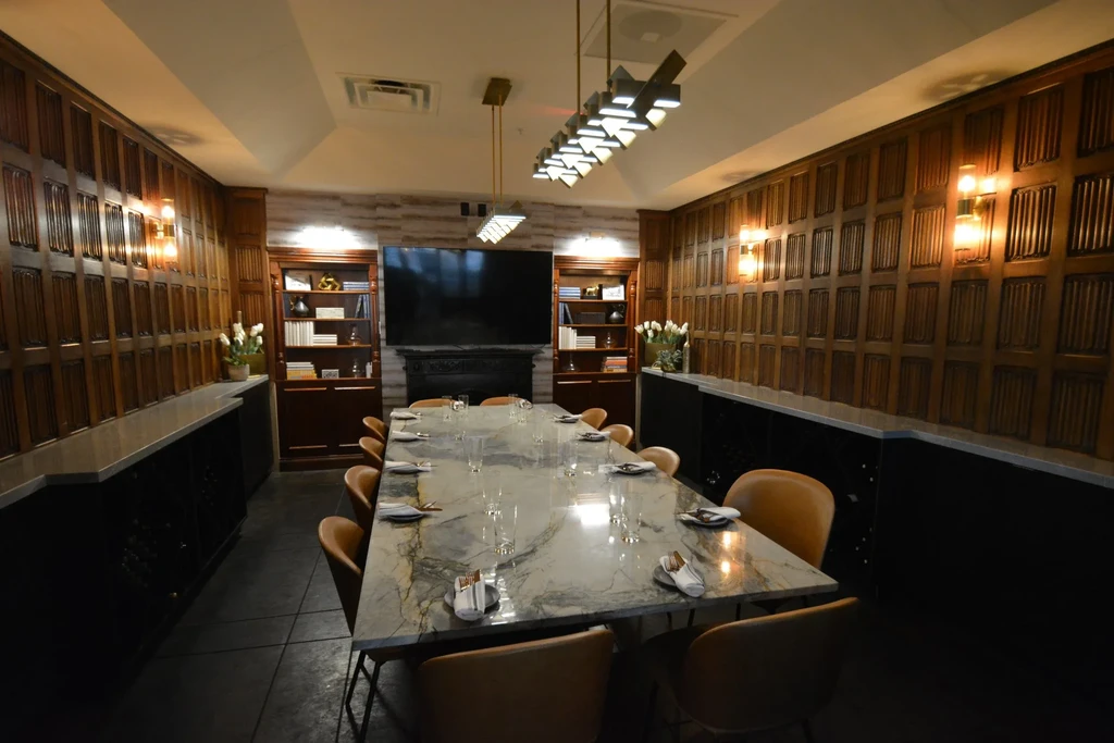 Private dining room with long marble table, chairs, TV, and fireplace.