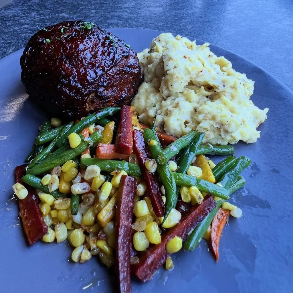 Plated meal with glazed meatloaf, mashed potatoes, and mixed vegetables.