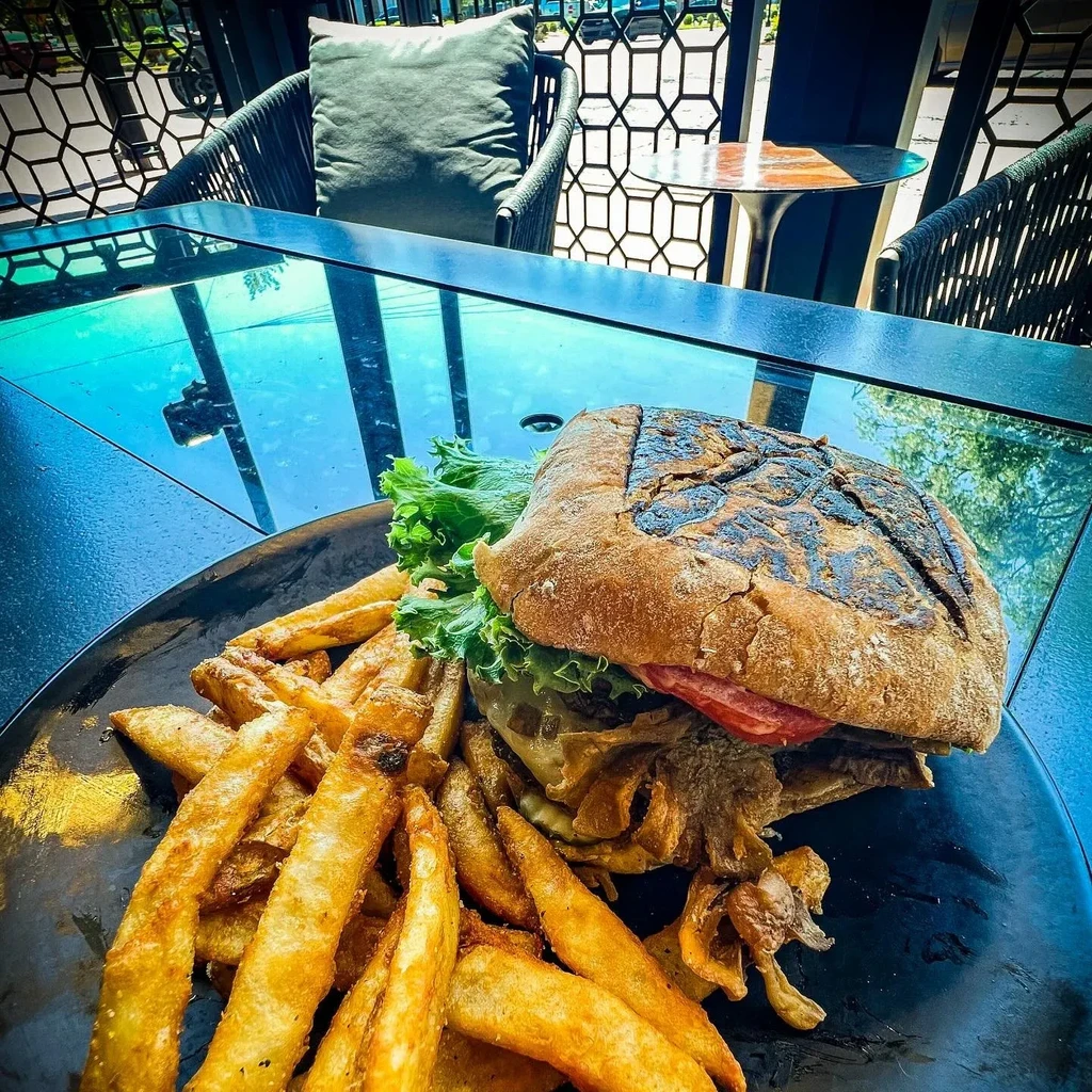 Rustic burger, french fries, and onion strings on a patio.