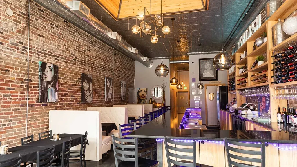 Modern restaurant interior with brick wall art and purple-lit bar.