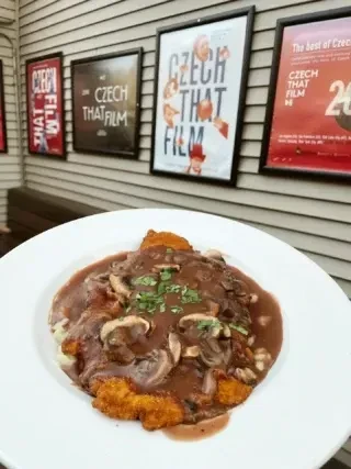Plate of breaded cutlet with mushroom gravy, herbs, and film posters.