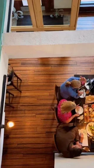 High-angle view of three people dining at a dark restaurant table.