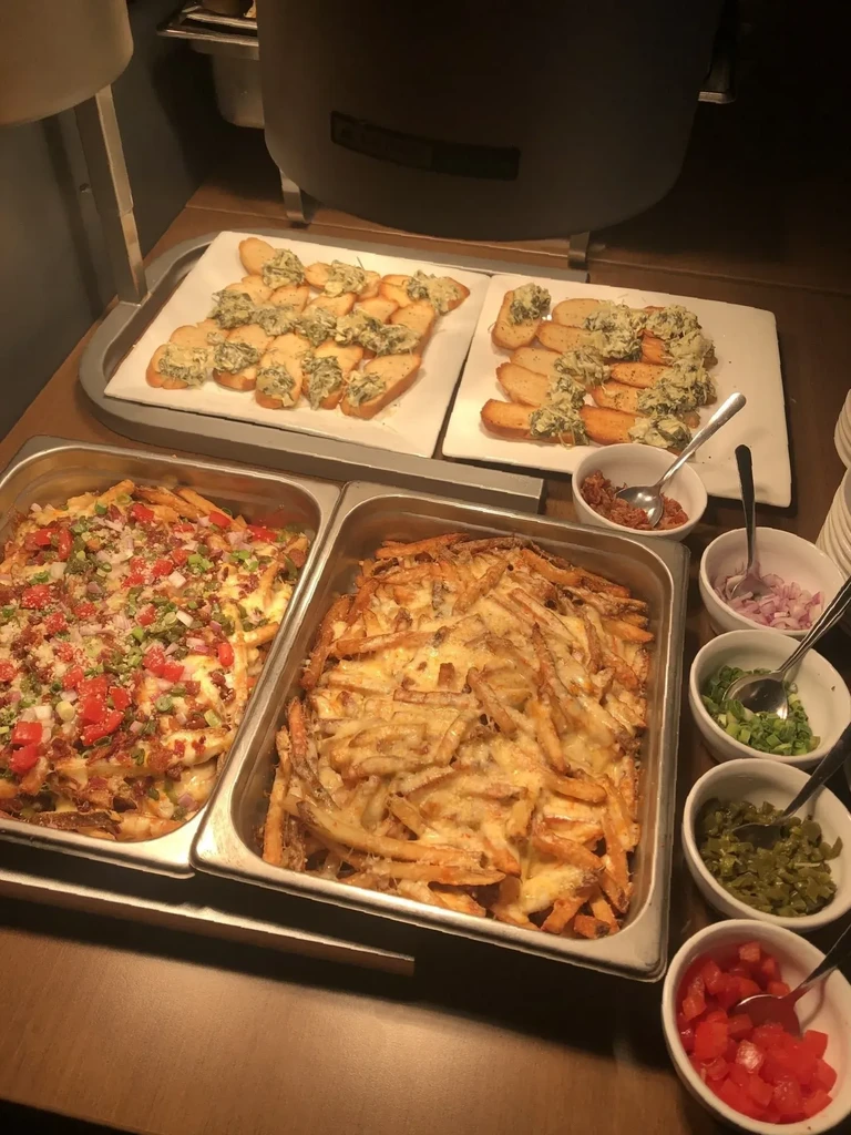 Food buffet with loaded fries, cheese fries, topping bowls, and bruschetta.