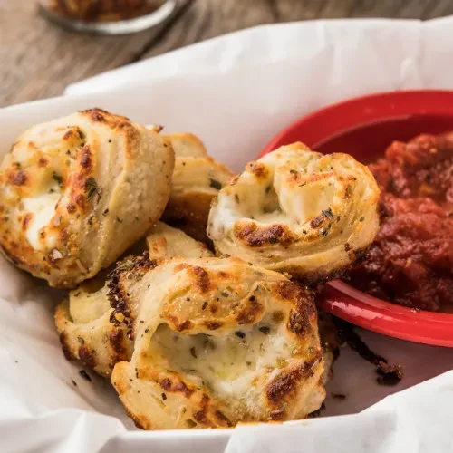 Golden-brown cheese bread bites with herbs and marinara sauce.