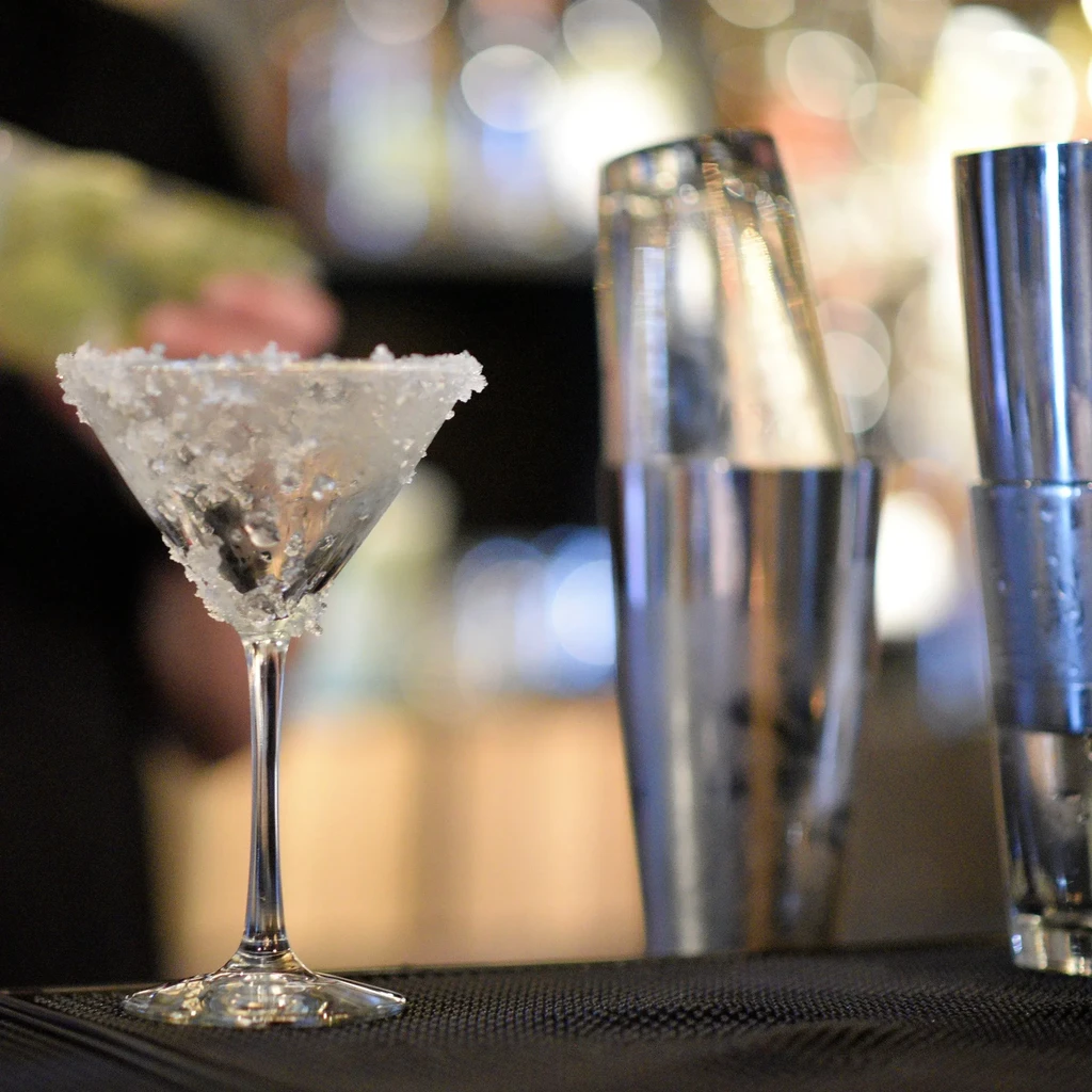Martini glass with clear liquid, ice, and thick frosty salt rim.