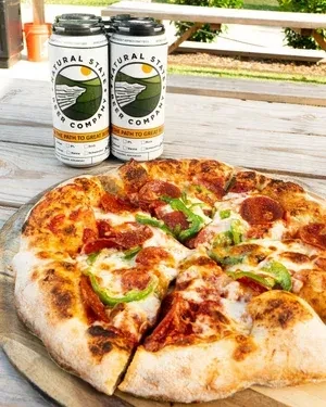 Pepperoni, green pepper pizza with melted cheese and two beer cans.