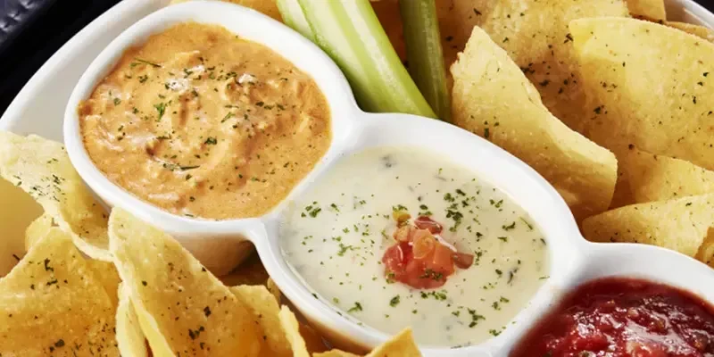 Tortilla chips served with queso, creamy white dip, and chunky salsa.