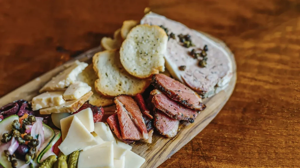 Charcuterie board with cheeses, cured meats, bread, and pickled vegetables.