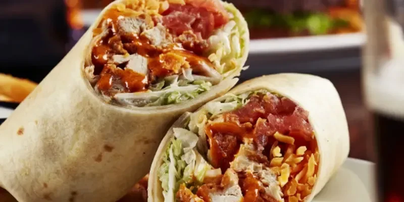 Halved buffalo chicken wrap with lettuce, tomato, and cheese.