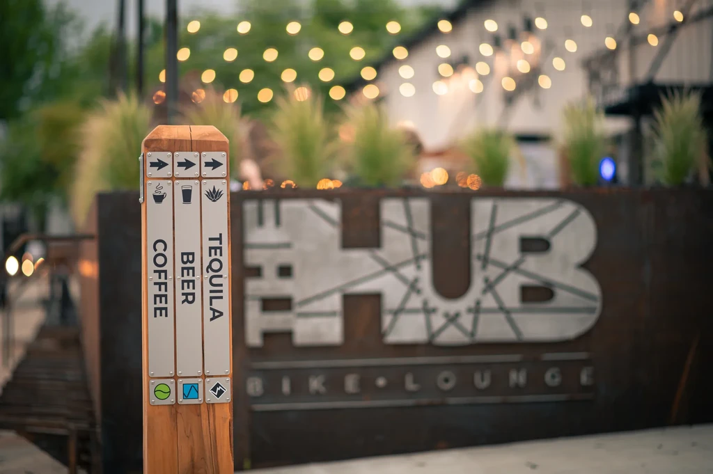 Rustic outdoor signpost with coffee, beer, tequila directions.