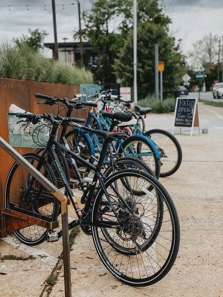 Bicycles parked at a weathered steel bike rack with a "PATIO OPEN" sign.