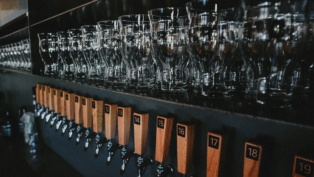 Row of numbered beer taps and clean, empty stemmed glasses.