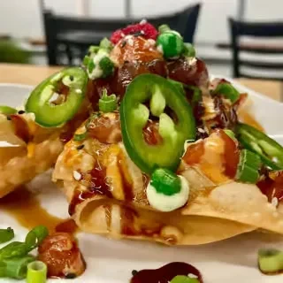 Deconstructed tuna poke on crispy wontons with edamame and two sauces.
