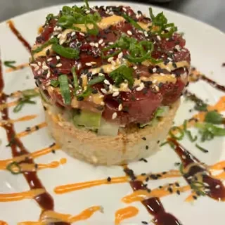 Tuna tartare stack with crispy rice, vegetables, and sauces.