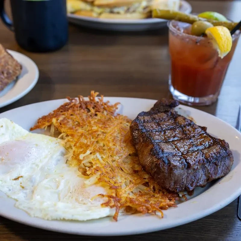 Grilled steak, hash browns, fried eggs, and Bloody Mary.