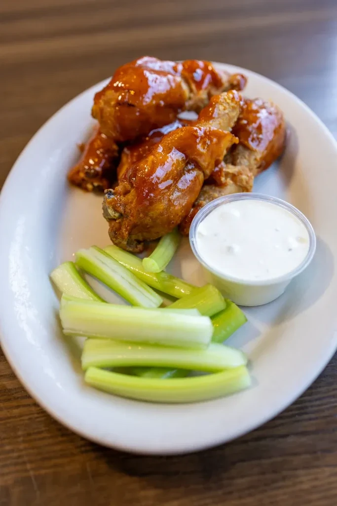 Glossy chicken wings, celery sticks, and creamy dipping sauce.