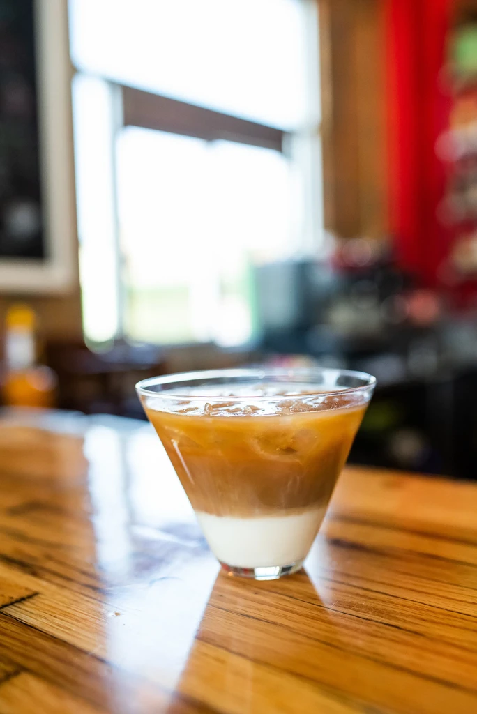 Layered iced drink with white and caramel in a V-shaped glass.