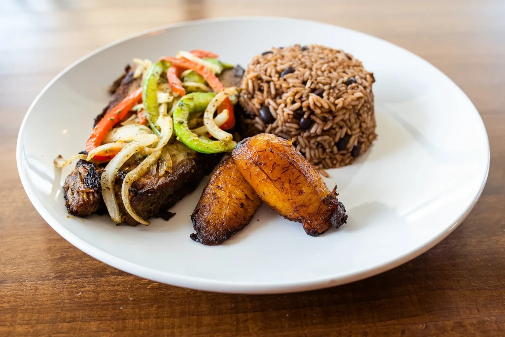 Plate with roasted meat, sautéed vegetables, rice with beans, plantains.
