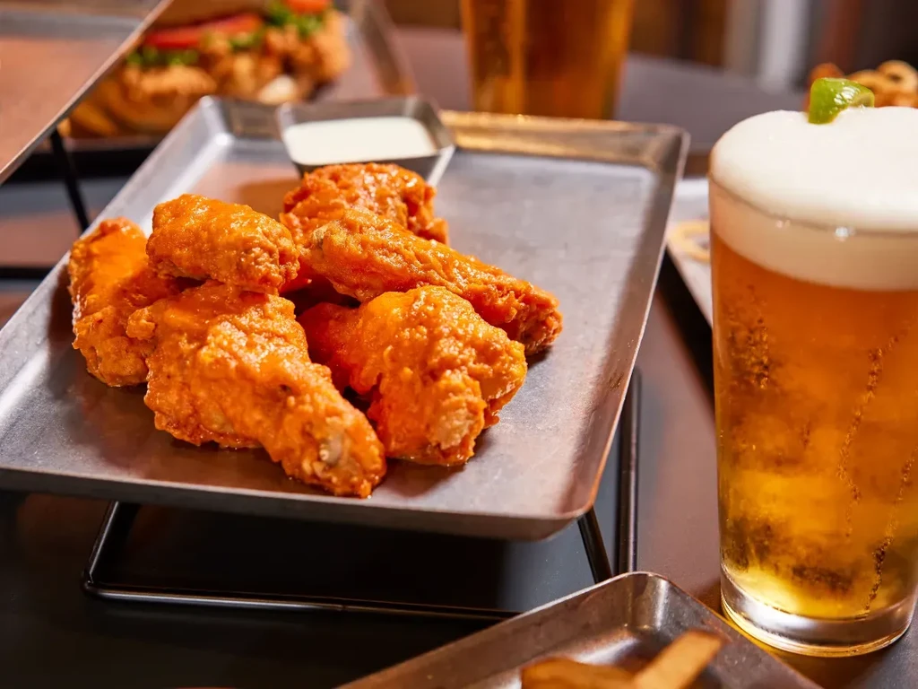Close-up of buffalo wings, white dip, and cold beer with lime.
