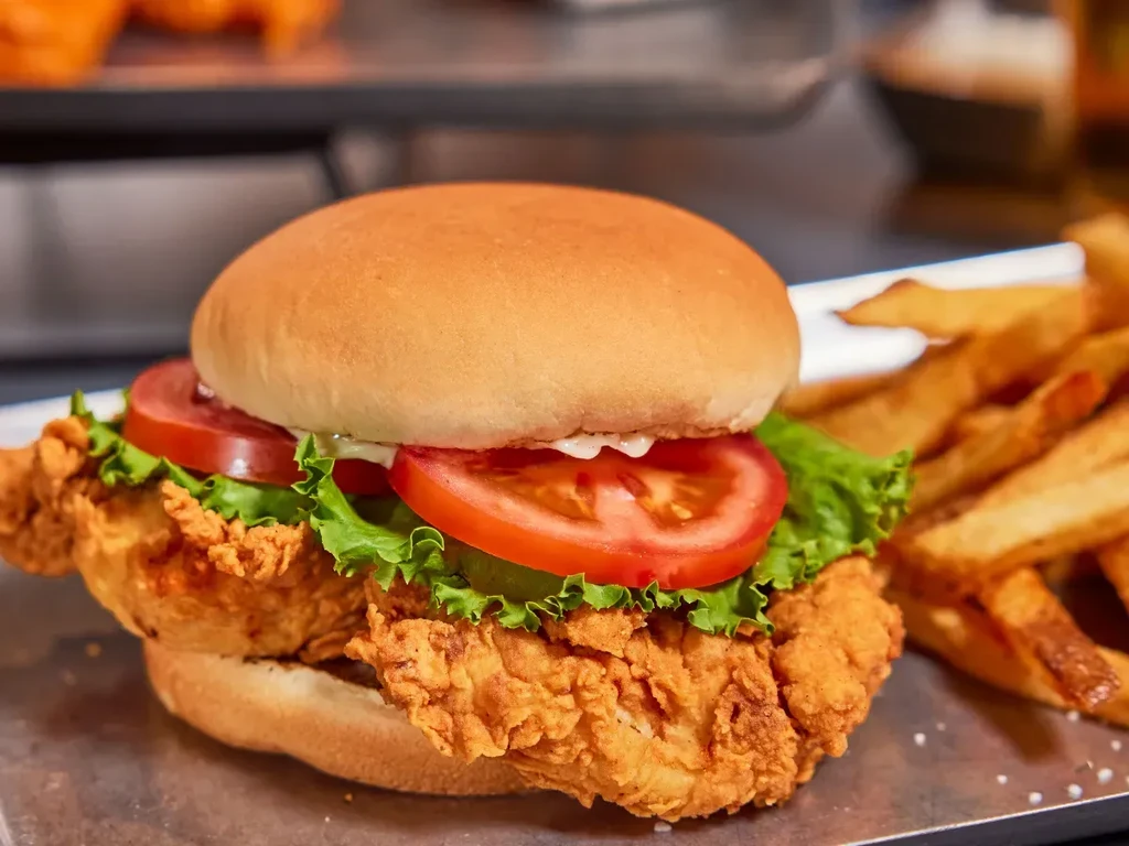 Crispy golden-brown fried chicken sandwich with lettuce, tomato, and fries.