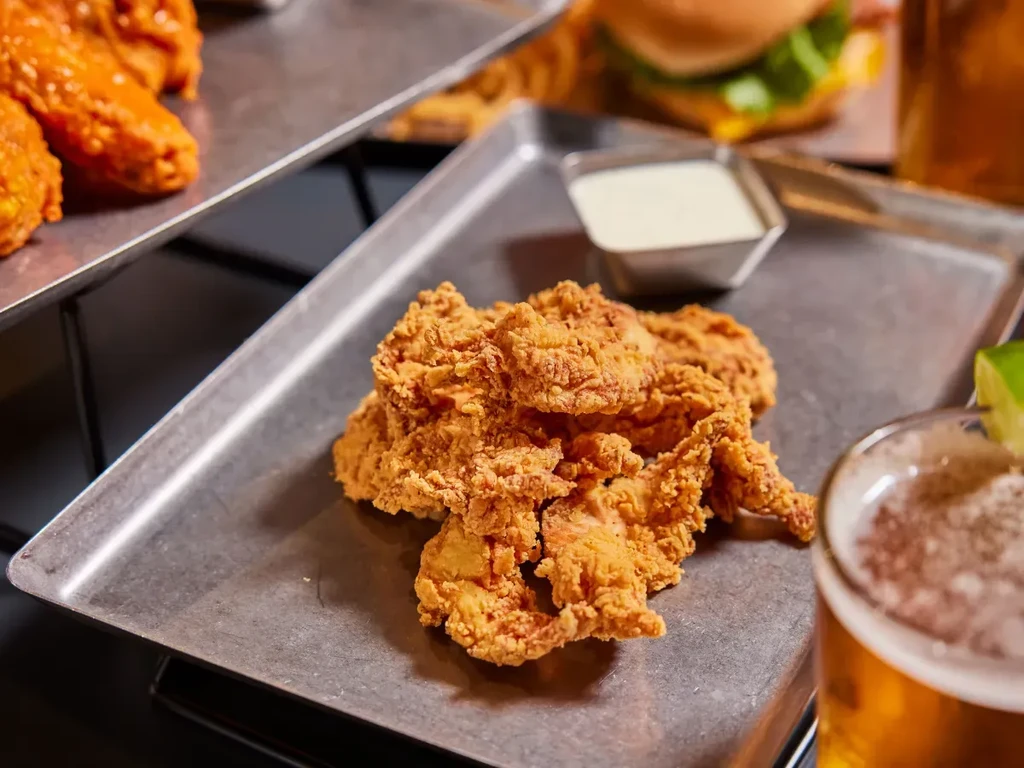 Crispy fried chicken tenders with dipping sauce and a beer.