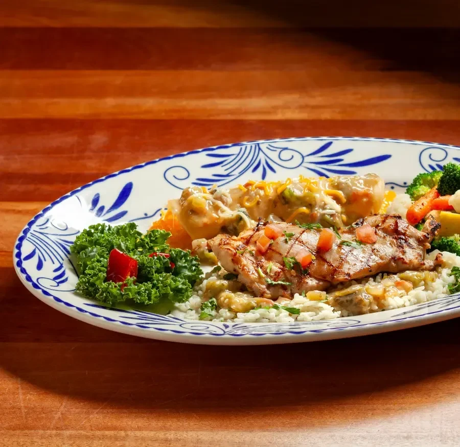Grilled chicken, rice, mixed vegetables, and cheesy casserole on a plate.