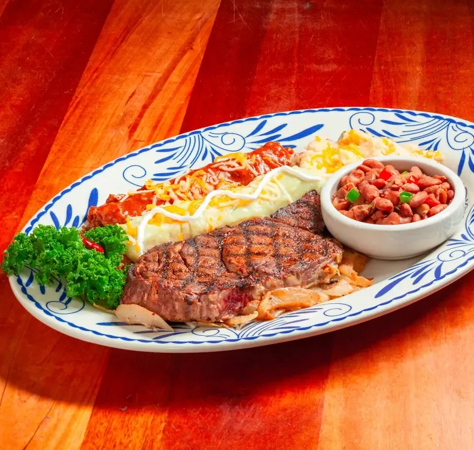 Grilled steak, red and white enchiladas, rice, beans, and garnish.
