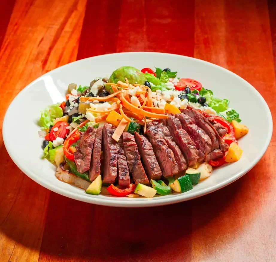 Grilled steak salad with avocado, cheese, and tortilla strips.
