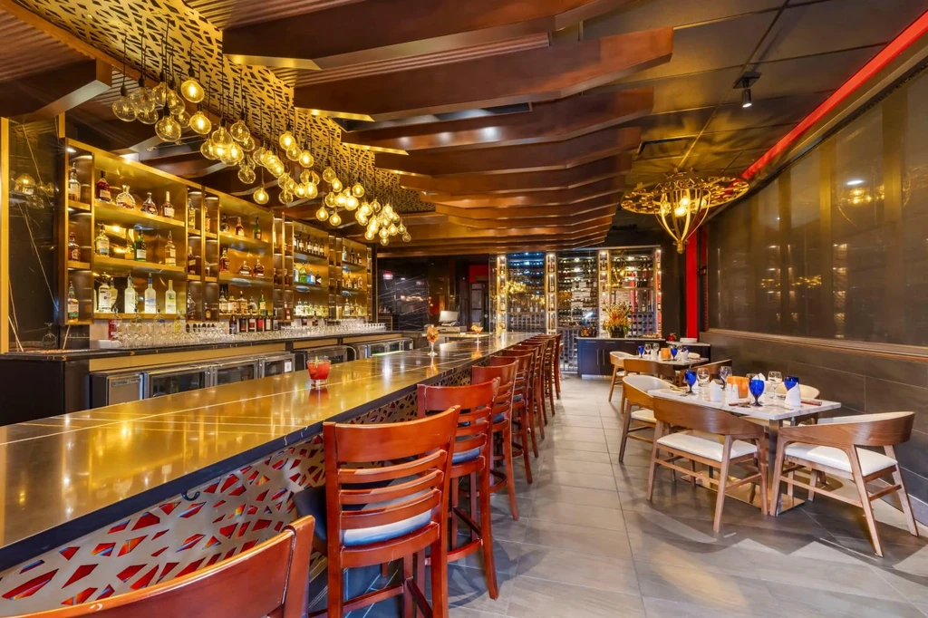 Restaurant interior with golden bar, pendant lights, and set tables.