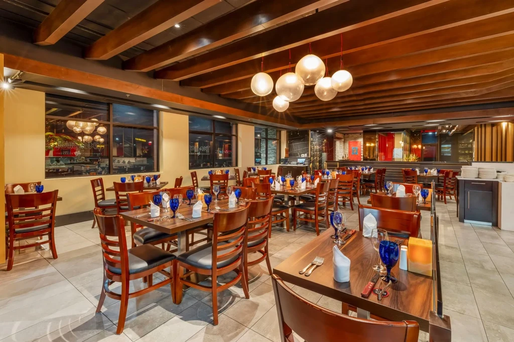 Empty modern restaurant dining room with wooden beams and set tables.