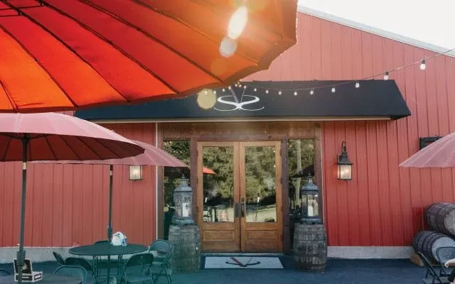 Warm red barn-style building with rustic doors and patio seating.