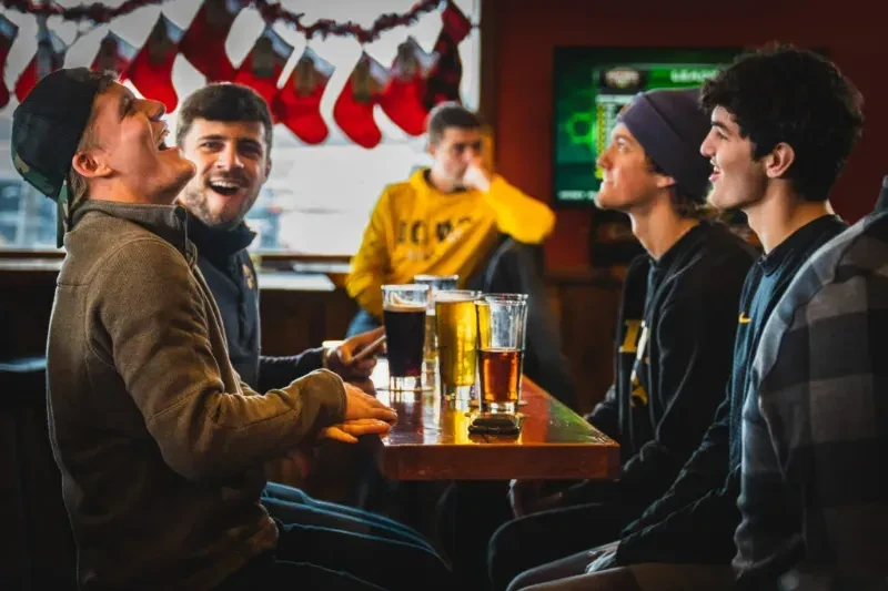 Young men laughing together in a festive pub.