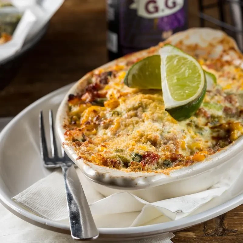 Golden-brown baked gratin in a ramekin, garnished with lime slices.