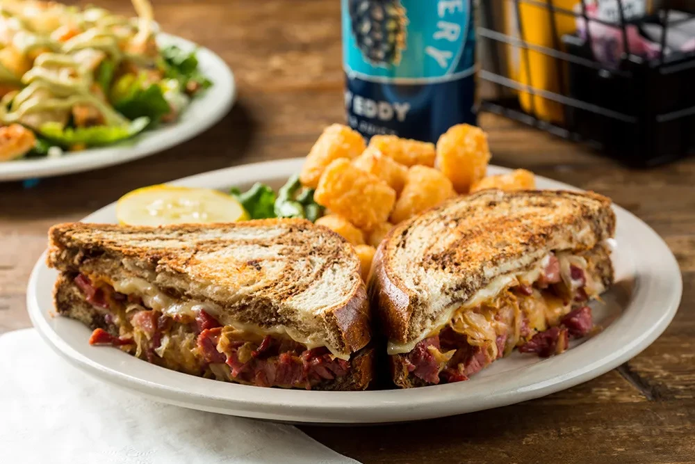 Classic Reuben sandwich with corned beef, cheese, sauerkraut, and tater tots.