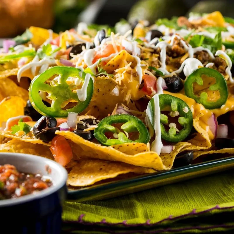 Close-up of loaded nachos with meat, cheese, jalapeños, and salsa.