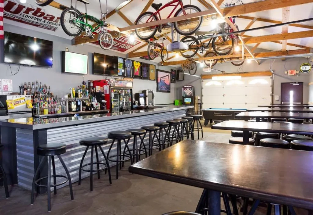 Industrial-style bar with corrugated counter, pool table, and suspended bicycles.