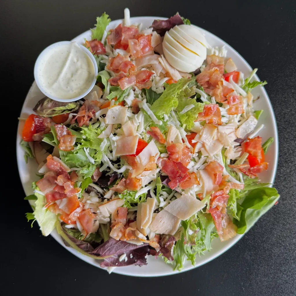 Loaded chef salad with turkey, egg, bacon, cheese, and dressing.