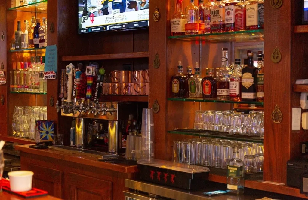 Well-stocked bar with bottles, beer taps, and college sports on TV.
