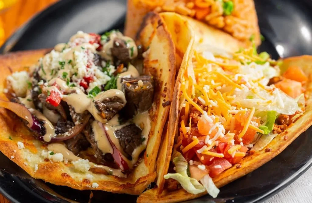 Close-up of two tacos: street-style and hard-shell, served with rice.