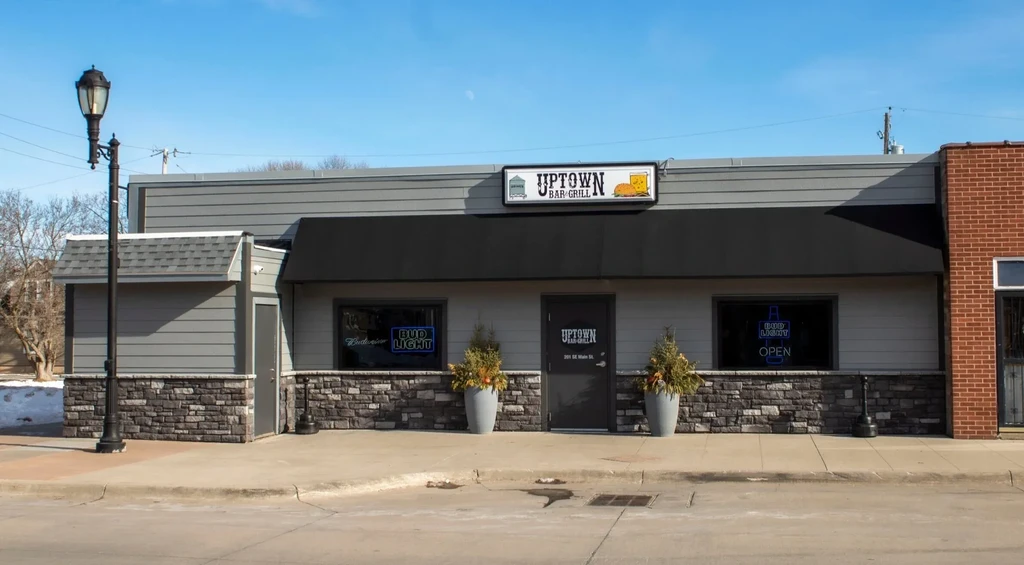 Uptown Bar-Grill exterior with modern design, black awning, and planters.