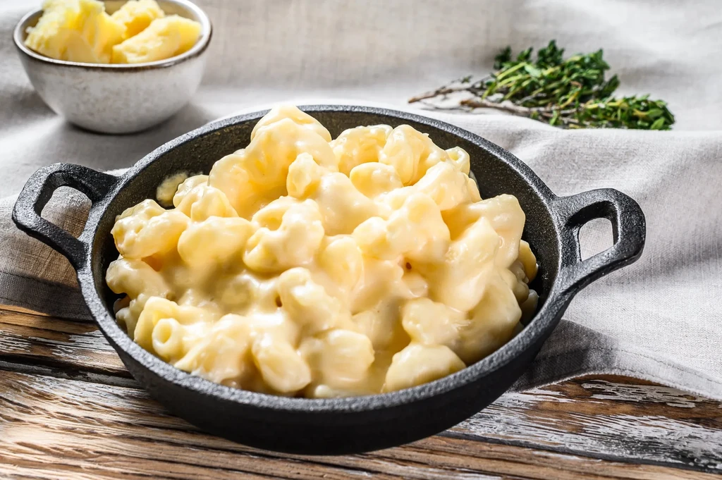 Creamy golden macaroni and cheese in a black cast iron pan.